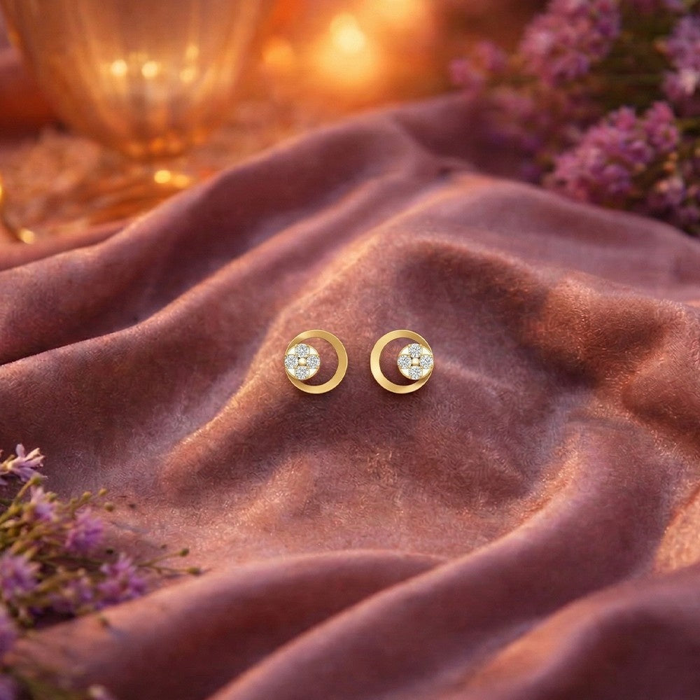 Gold and diamond earrings on a soft fabric background with flowers.