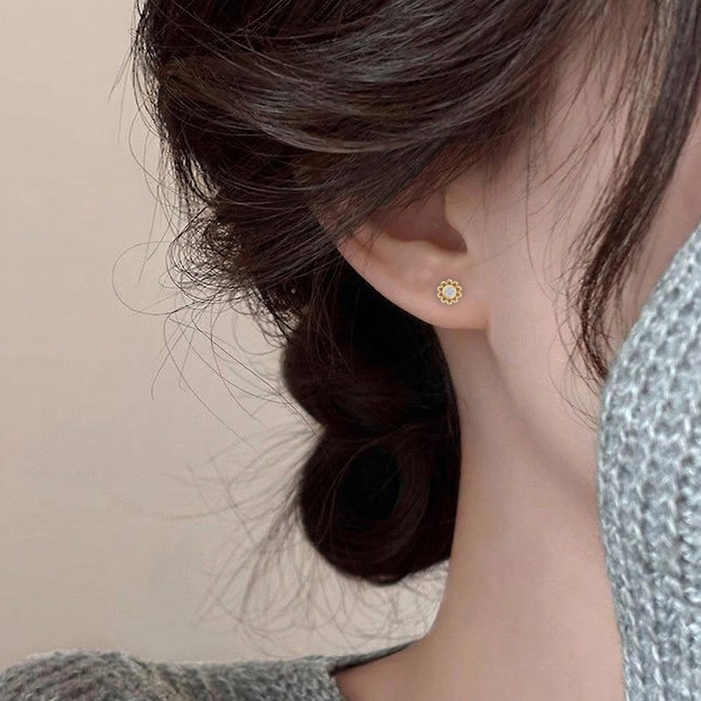 Close-up shot of a gold and diamond floral stud earring.