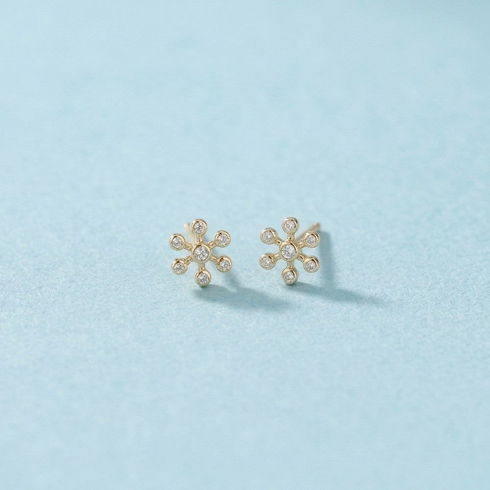 Gold and diamond floral stud earring on a light blue background.