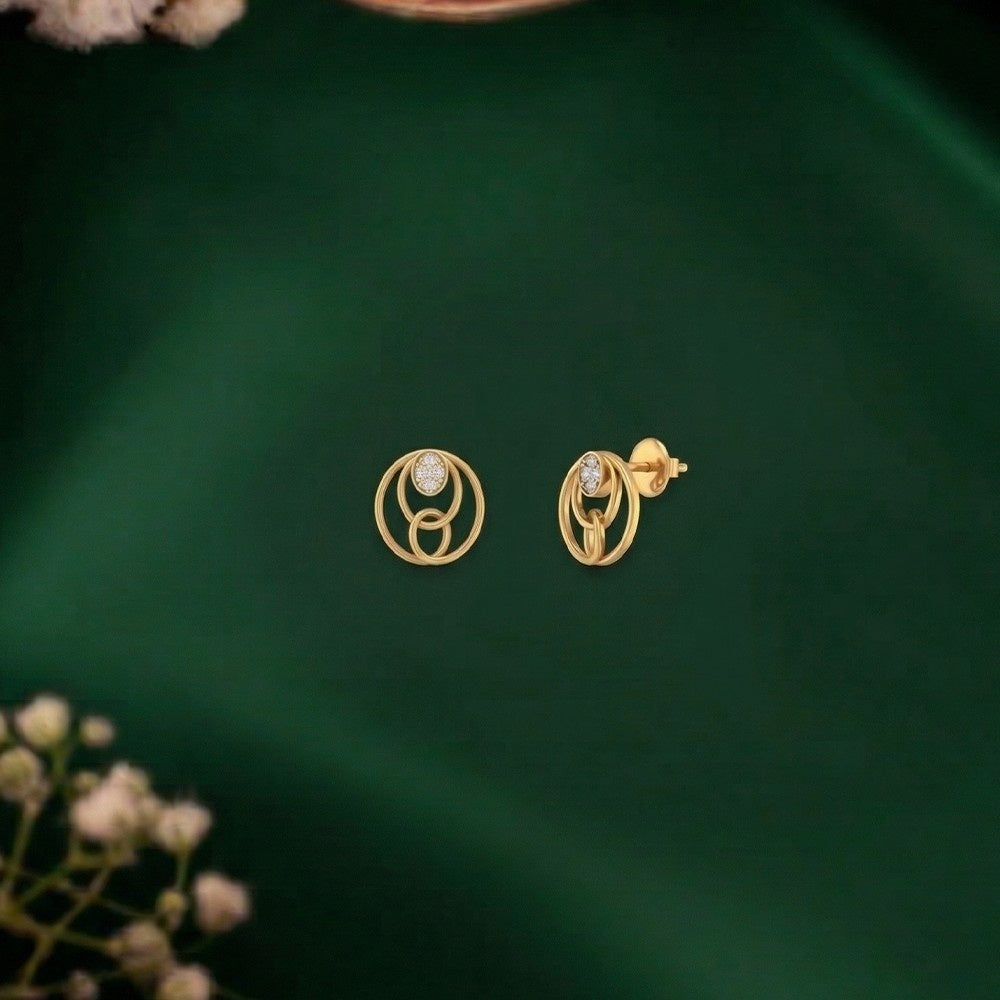 Gold and diamond round-shaoped stud earring on a green surface.