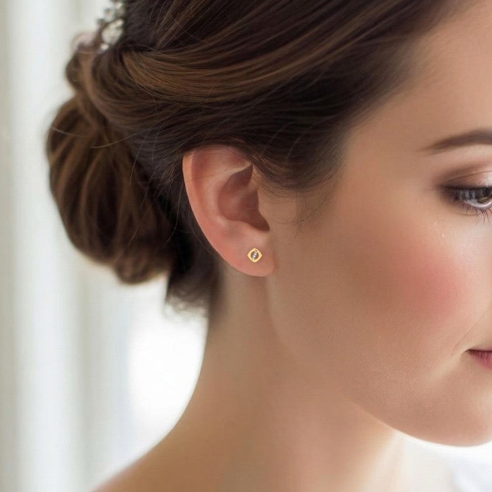 Close-up of a woman wearing gold and diamond stud earrings.