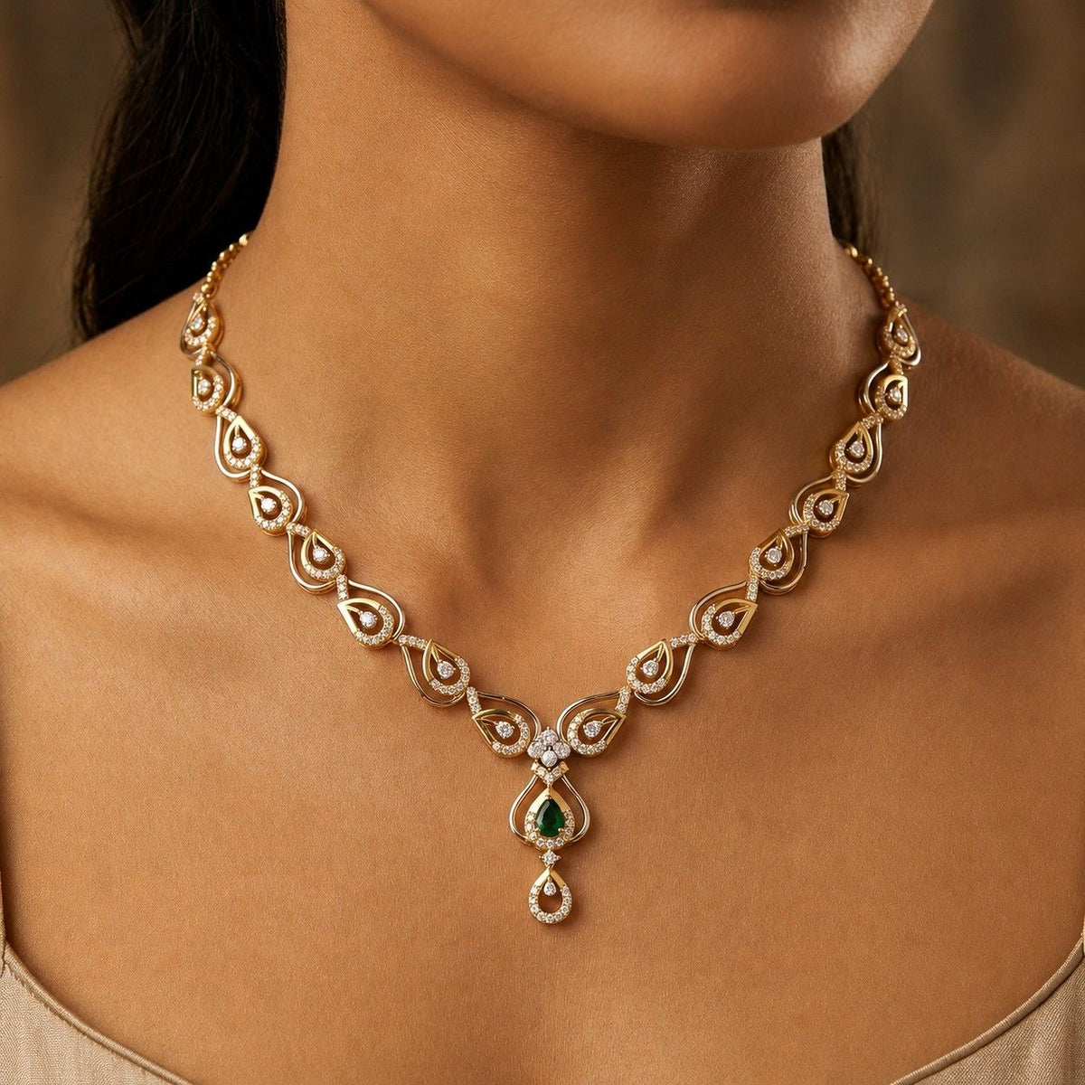 A close-up of a model's neck wearing a delicate gold necklace with a green teardrop gemstone.