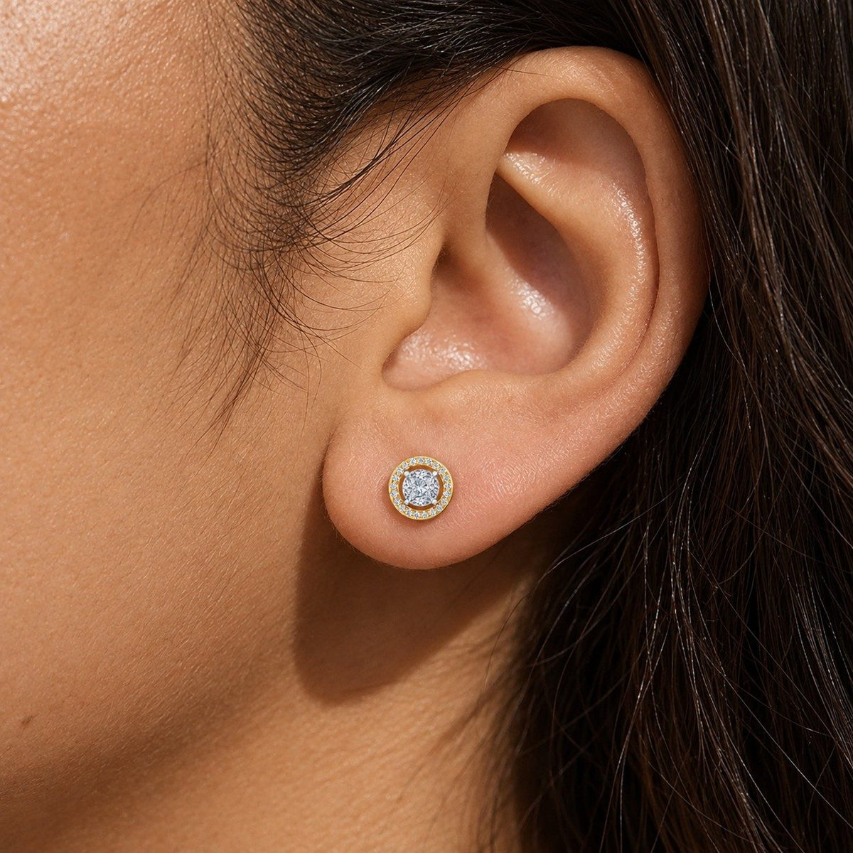 A close-up of a person's ear wearing a small round stud earring.