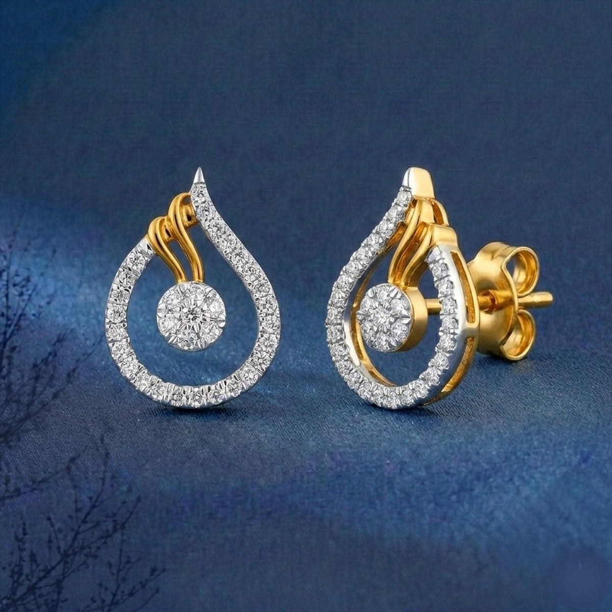 A pair of gold and diamond teardrop-shaped stud earrings and round center diamond, displayed on a dark blue textured background.