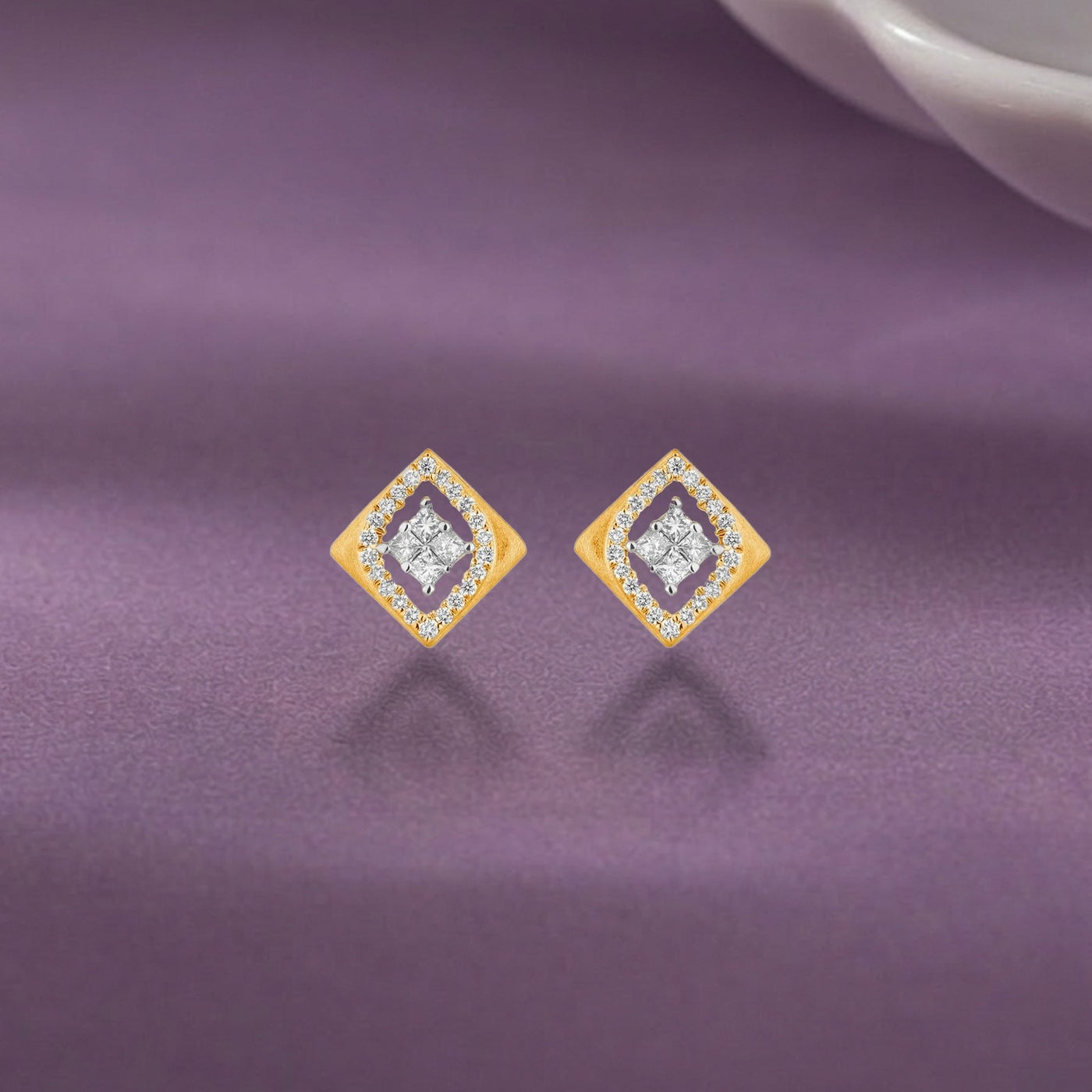 Gold and diamond stud earring with square-shaped on a purple surface.