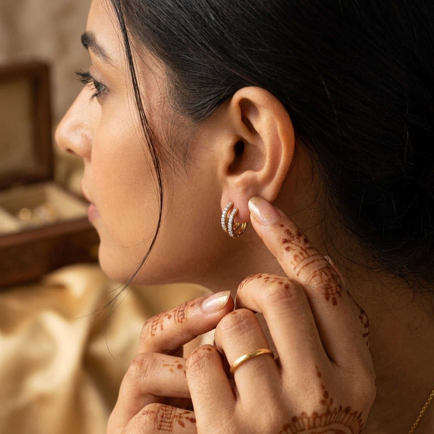 A close-up lifestyle shot of a woman wearing a pair of diamond huggie hoop earrings.