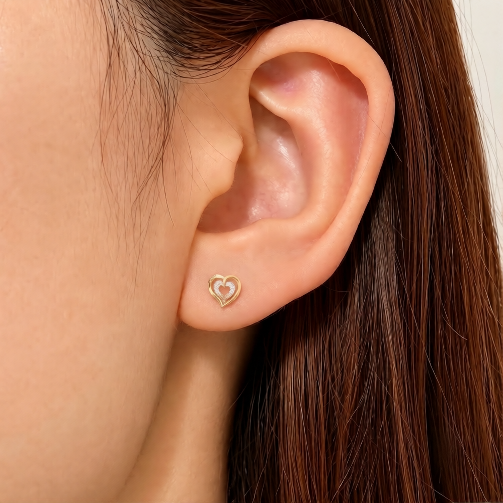 Close-up shot of a gold and diamond heart-shaped stud earring.