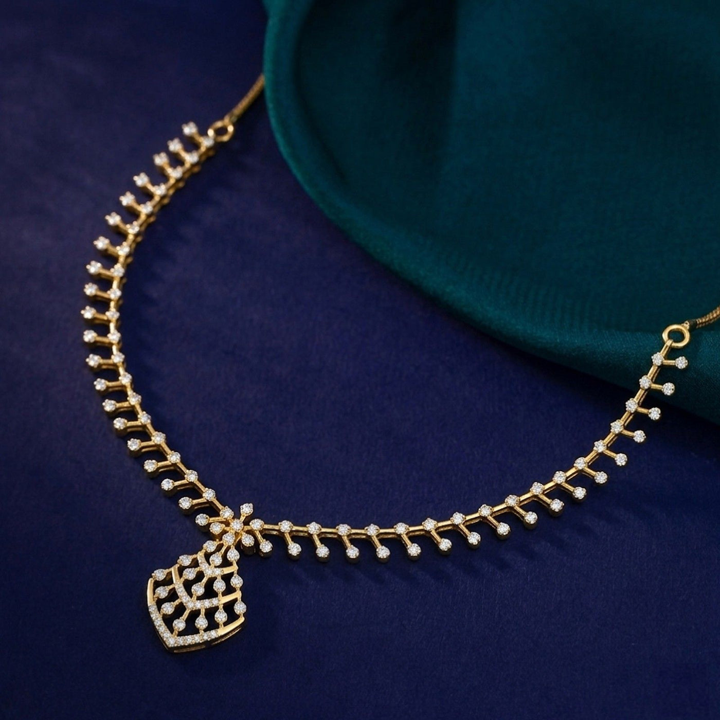 Gold and diamond necklace, displayed on a dark navy fabric background with a teal fabric accent.