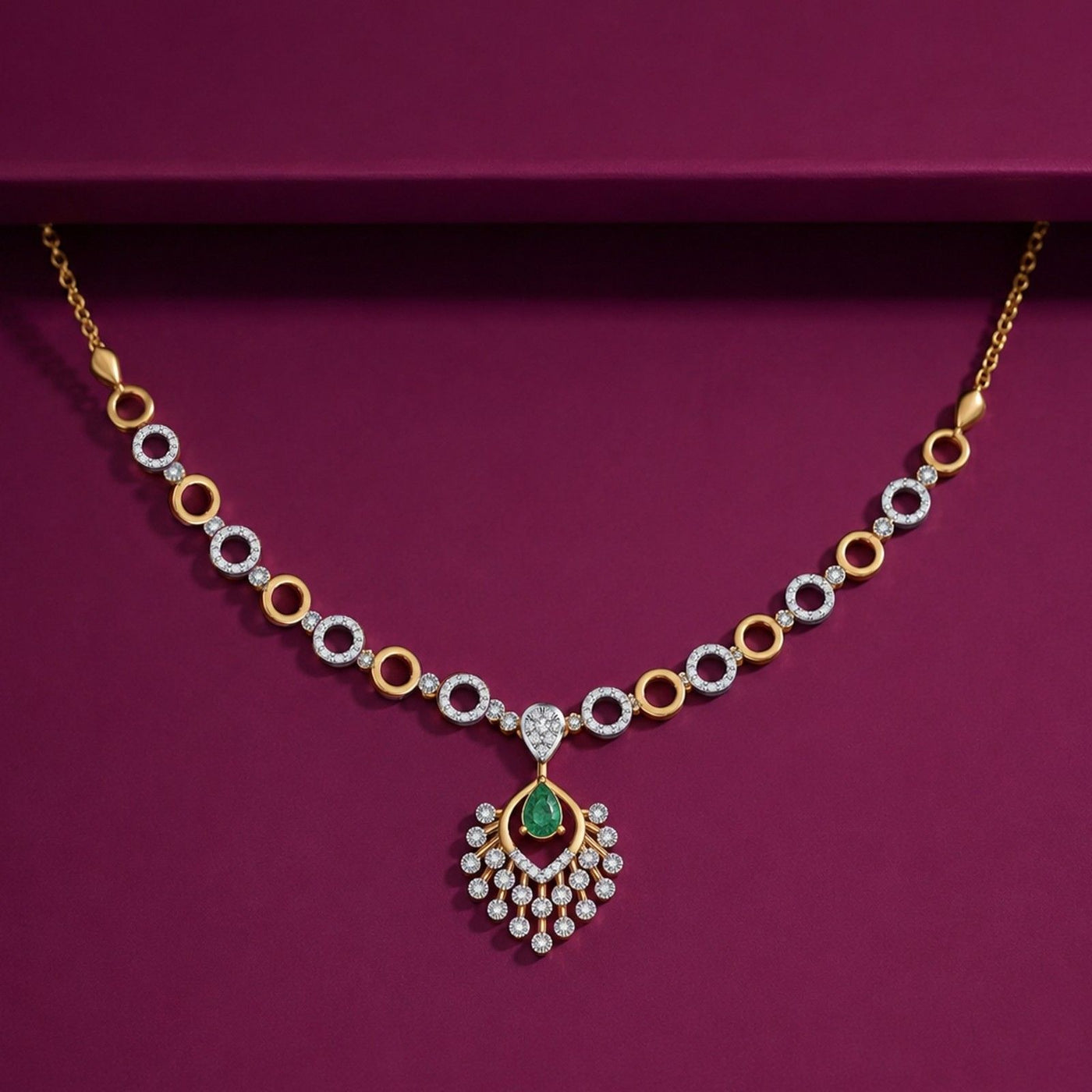 Gold and diamond necklace featuring a central emerald-cut green teardrop.