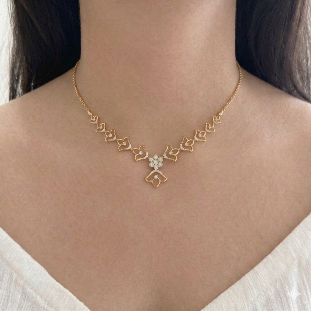 A delicate gold chain necklace with a central floral motif, worn on a model's neck.