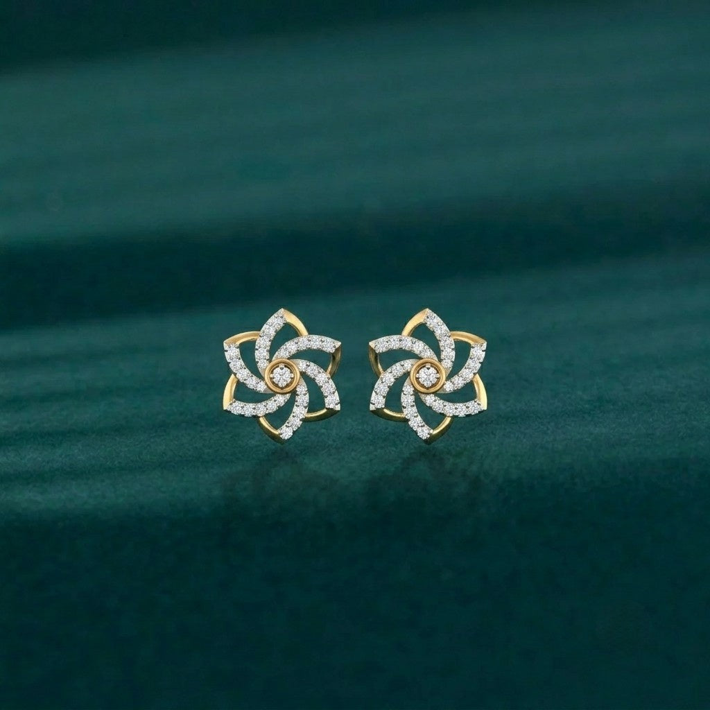 A pair of gold flower-shaped stud earrings, displayed on a dark teal textured fabric background.