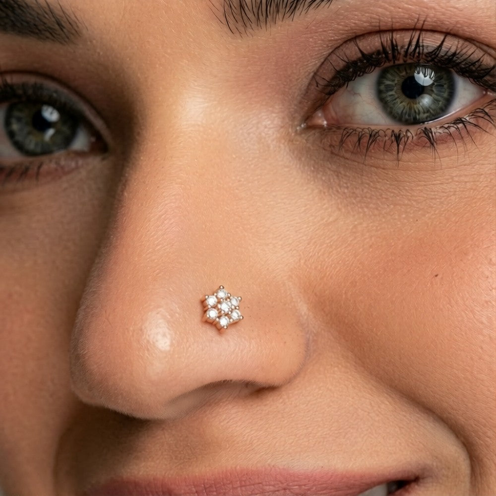 A close-up of a person's nose wearing a small gold flower-shaped stud.