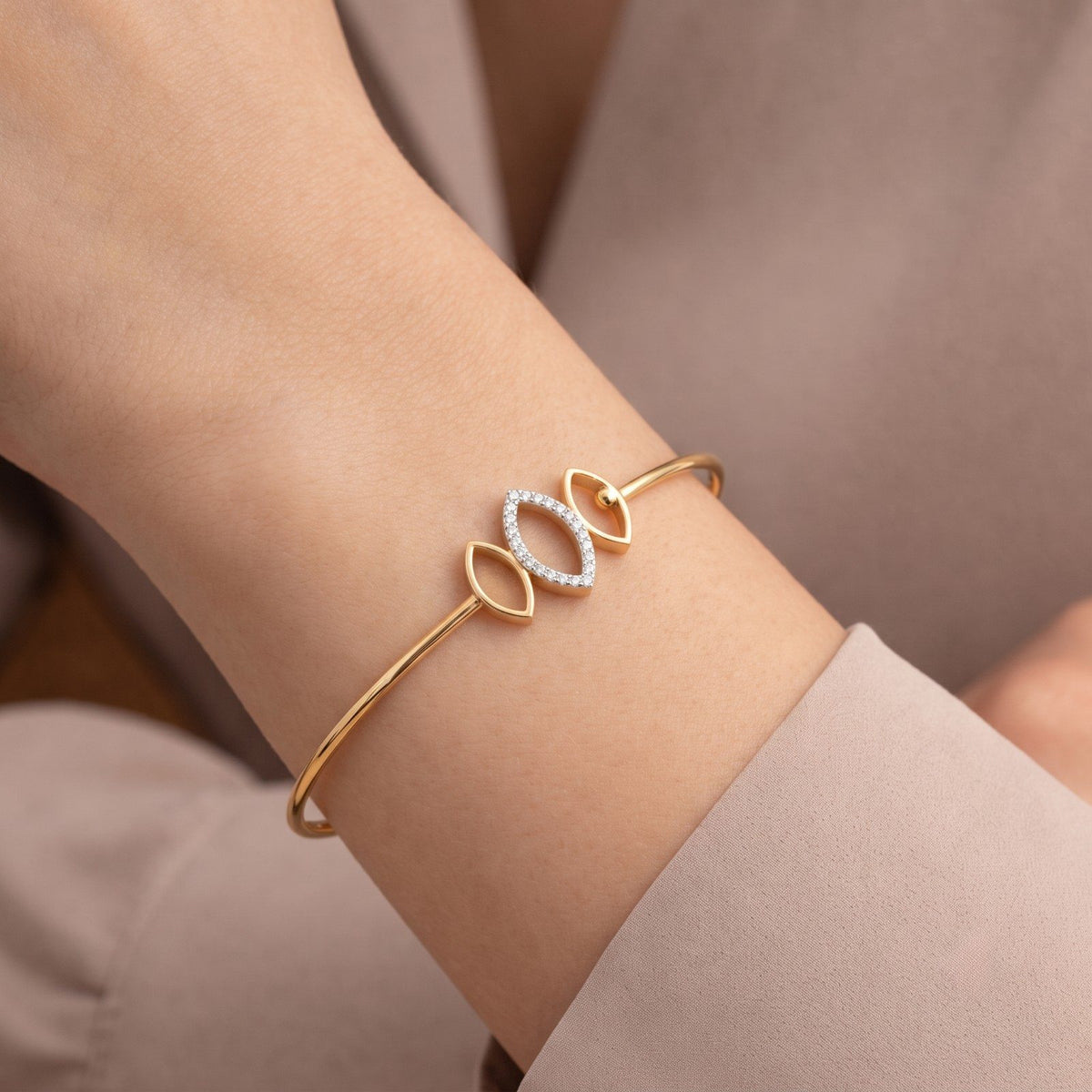 Gold diamond bracelet with elegant marquise geometric design on person hand.