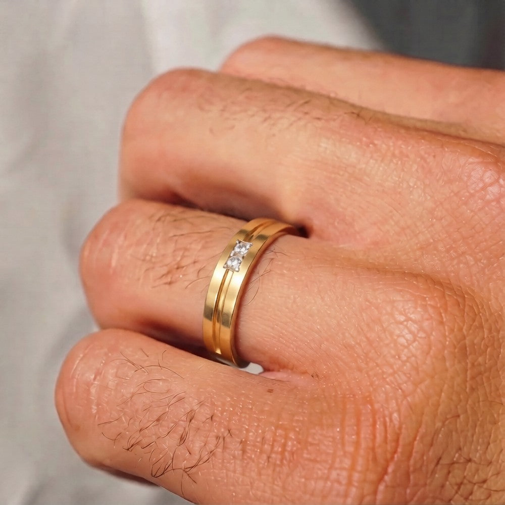 Gold ring with a diamond on a person's finger against a neutral background.