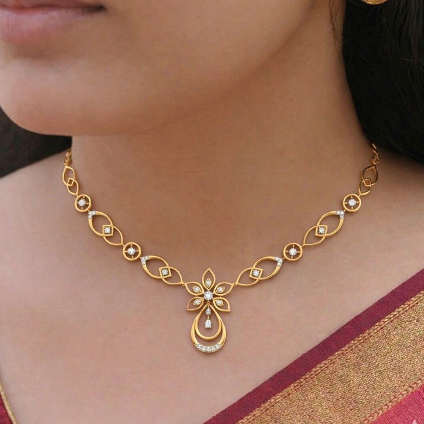 Gold necklace with floral and teardrop motifs, worn on a model's neck.