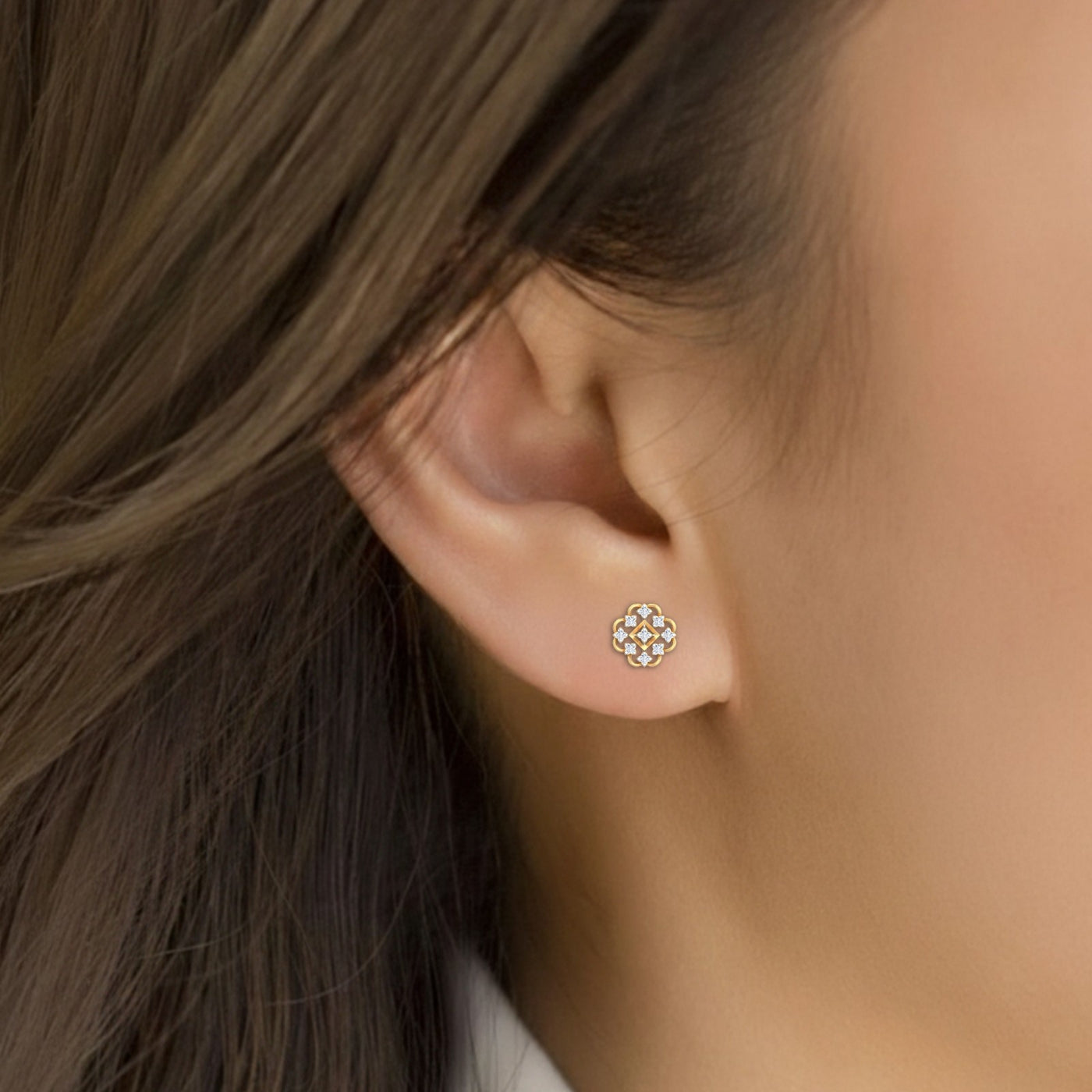 Close-up shot of a gold and diamond stud earring with floral-design.