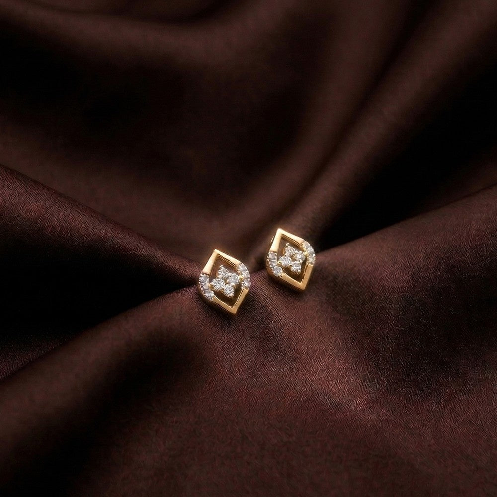 Gold and diamond stud earrings on a brown surface.