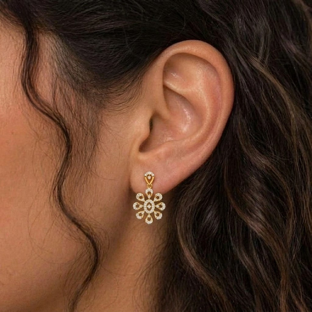 A close-up of a woman's ear wearing a delicate gold dangle earring.