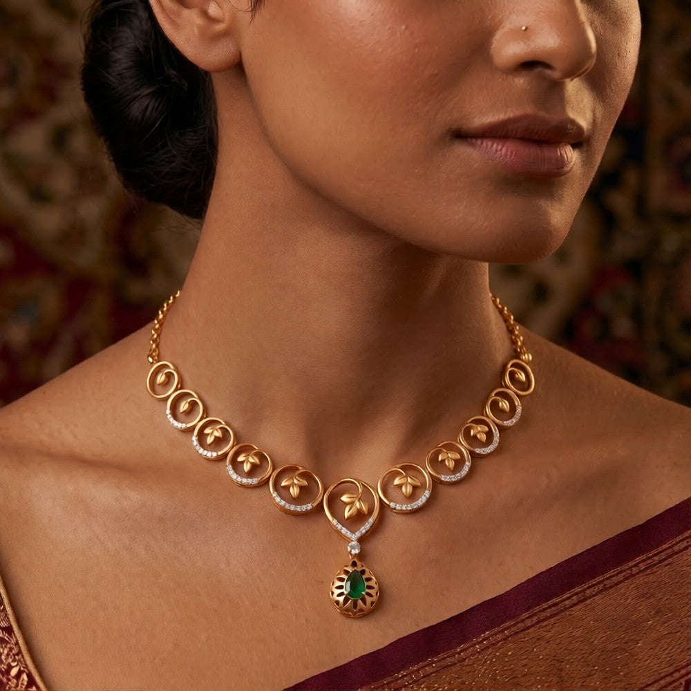 A close-up lifestyle shot of a model wearing a gold and diamond necklace set with a green gemstone.