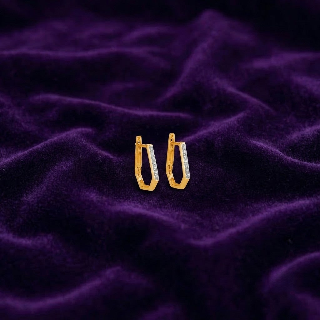 A pair of gold hoop earrings, displayed on a textured purple velvet fabric background.