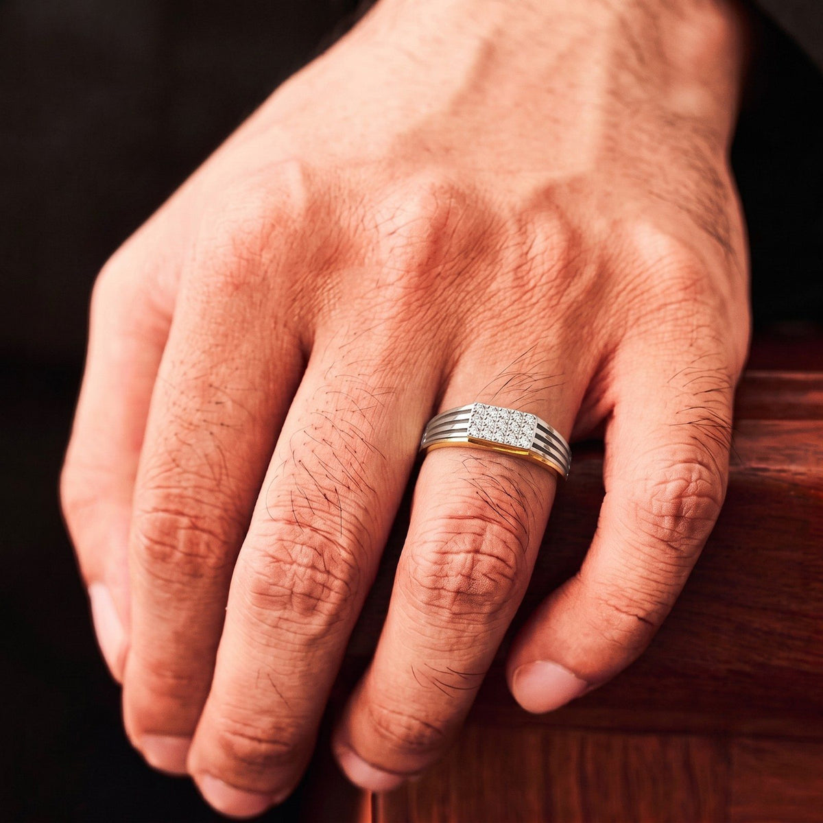 Gold and diamond band ring for men with diamond cluster on person finger.