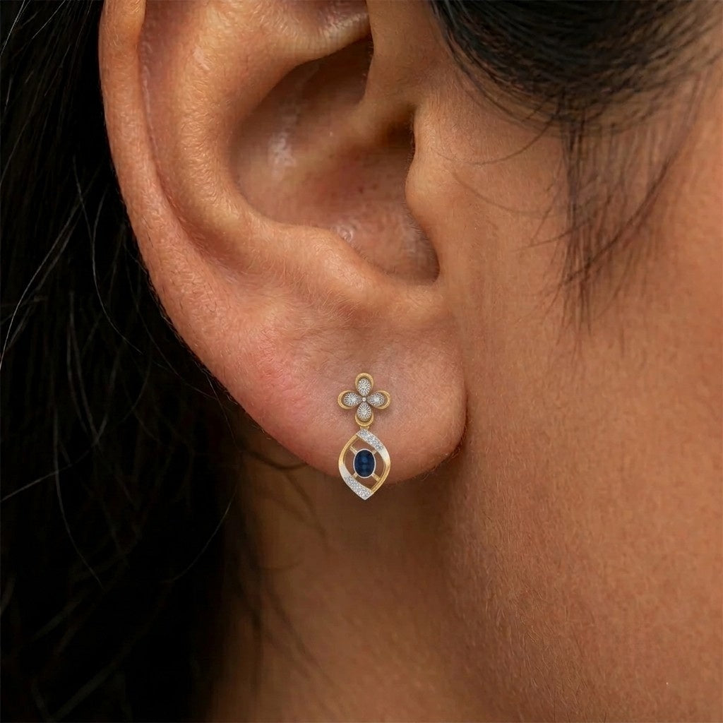 Close-up shot of a gold and diamond drop earrings with sapphiare gemstones.