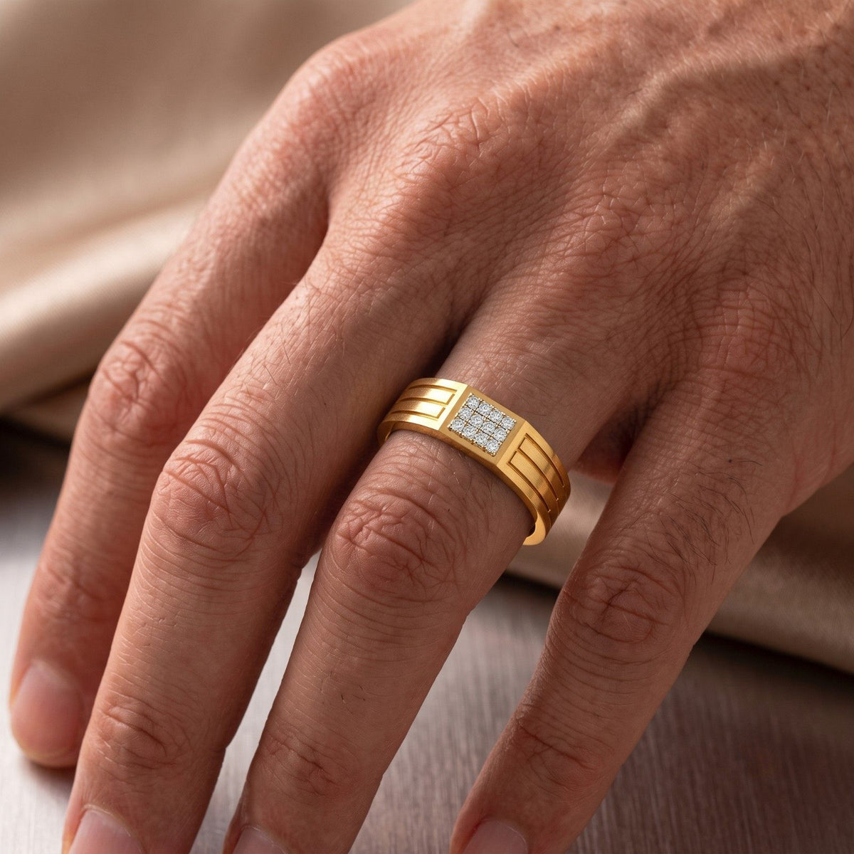 A close-up of a hand wearing a gold and diamond band ring.