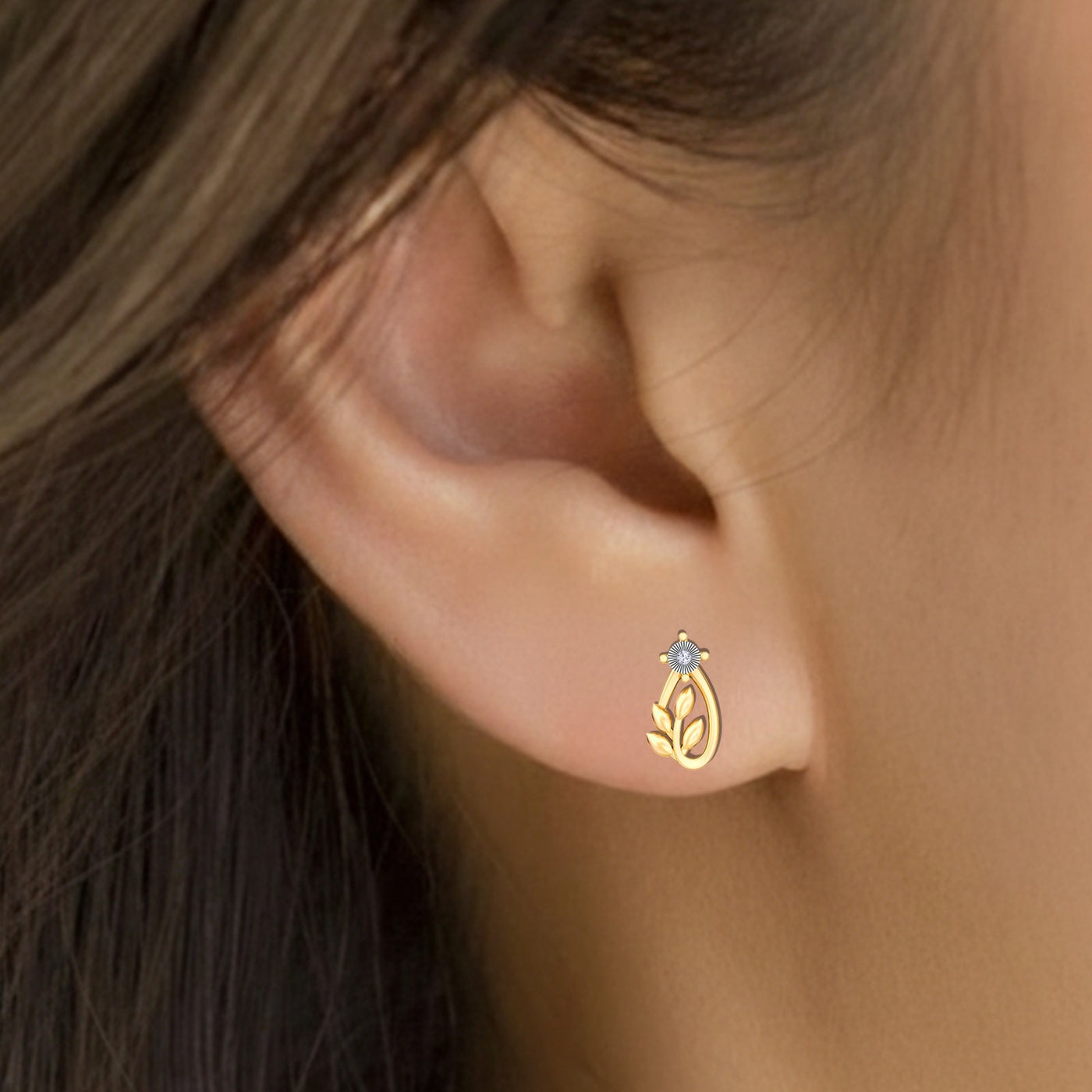 Close-up shot of gold and diamond stud earrings with leaf design.