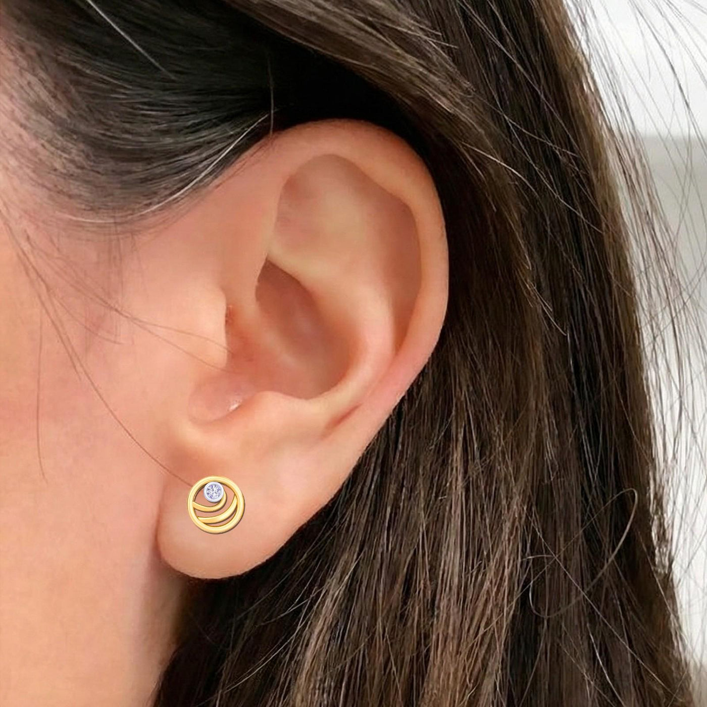 Close-up of an ear wearing a gold and diamond round-shaped stud earring.