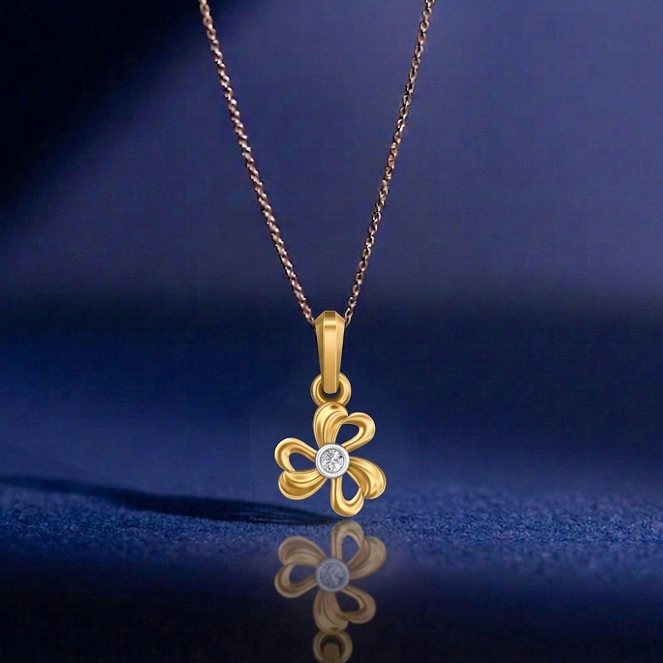 Gold necklace with a clover-shaped pendant on a blue background
