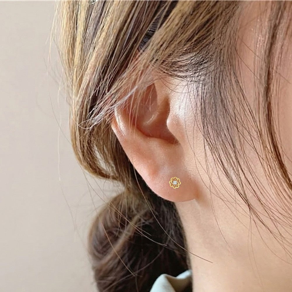 Close-up of an ear of wearing a gold and diamond floral earring.