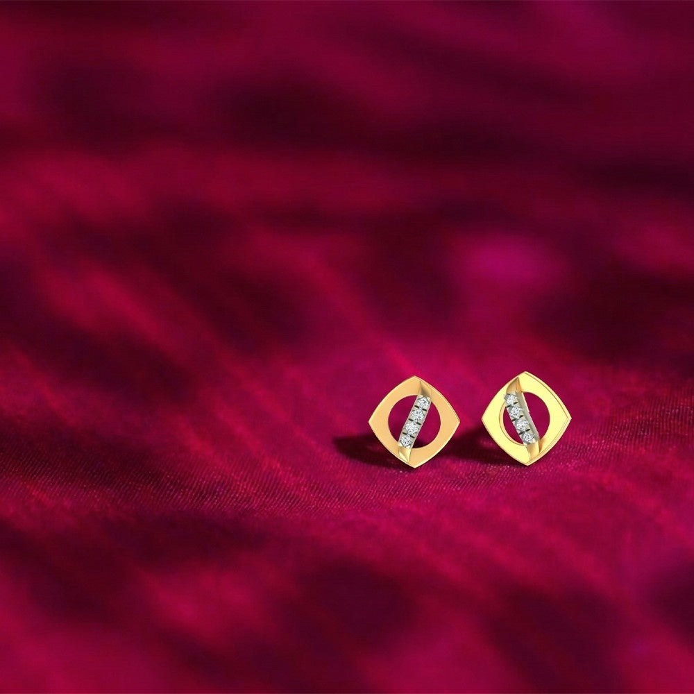 Gold and diamond stud earrings on a red fabric background.