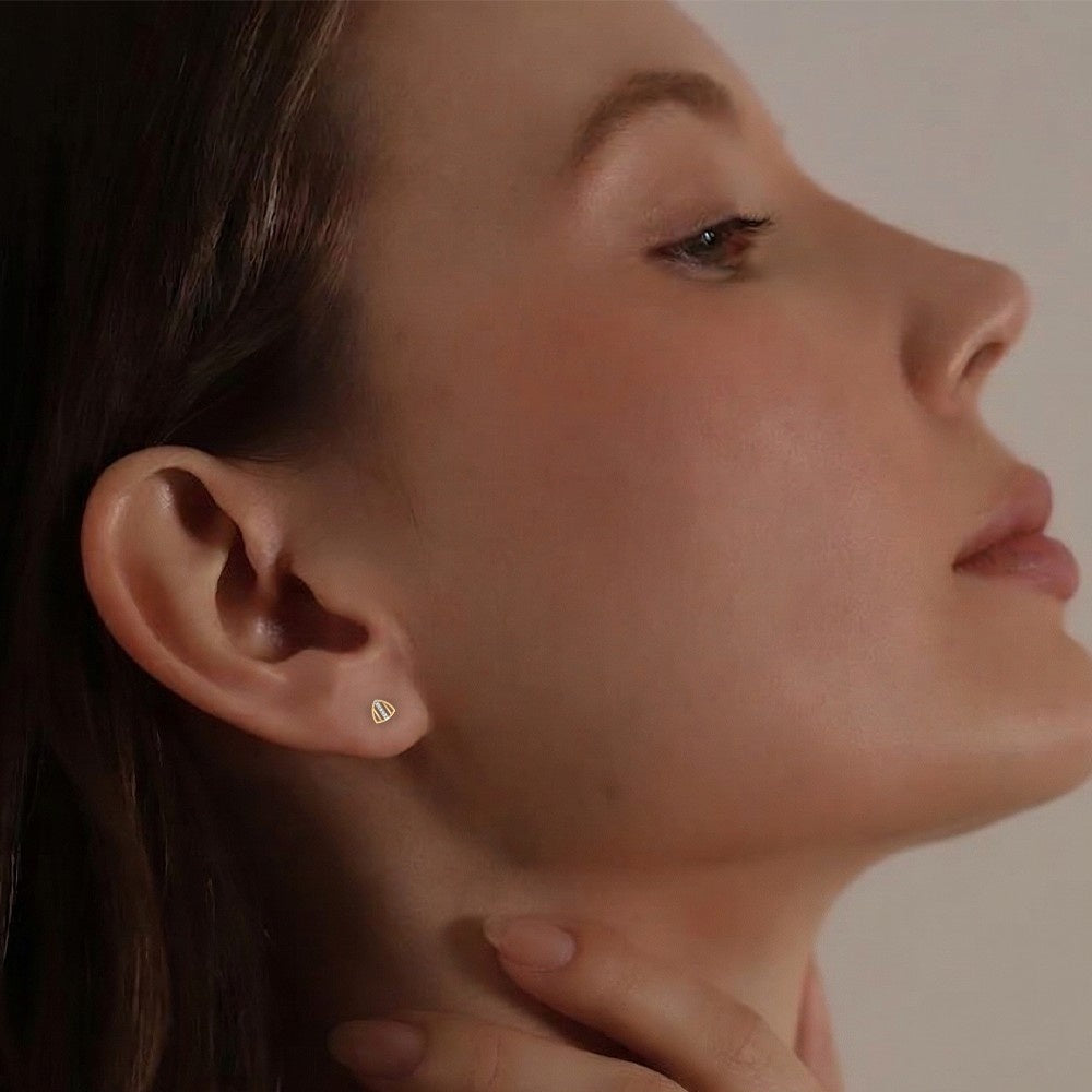 Close-up of a person wearing a gold earring with a triangle design.