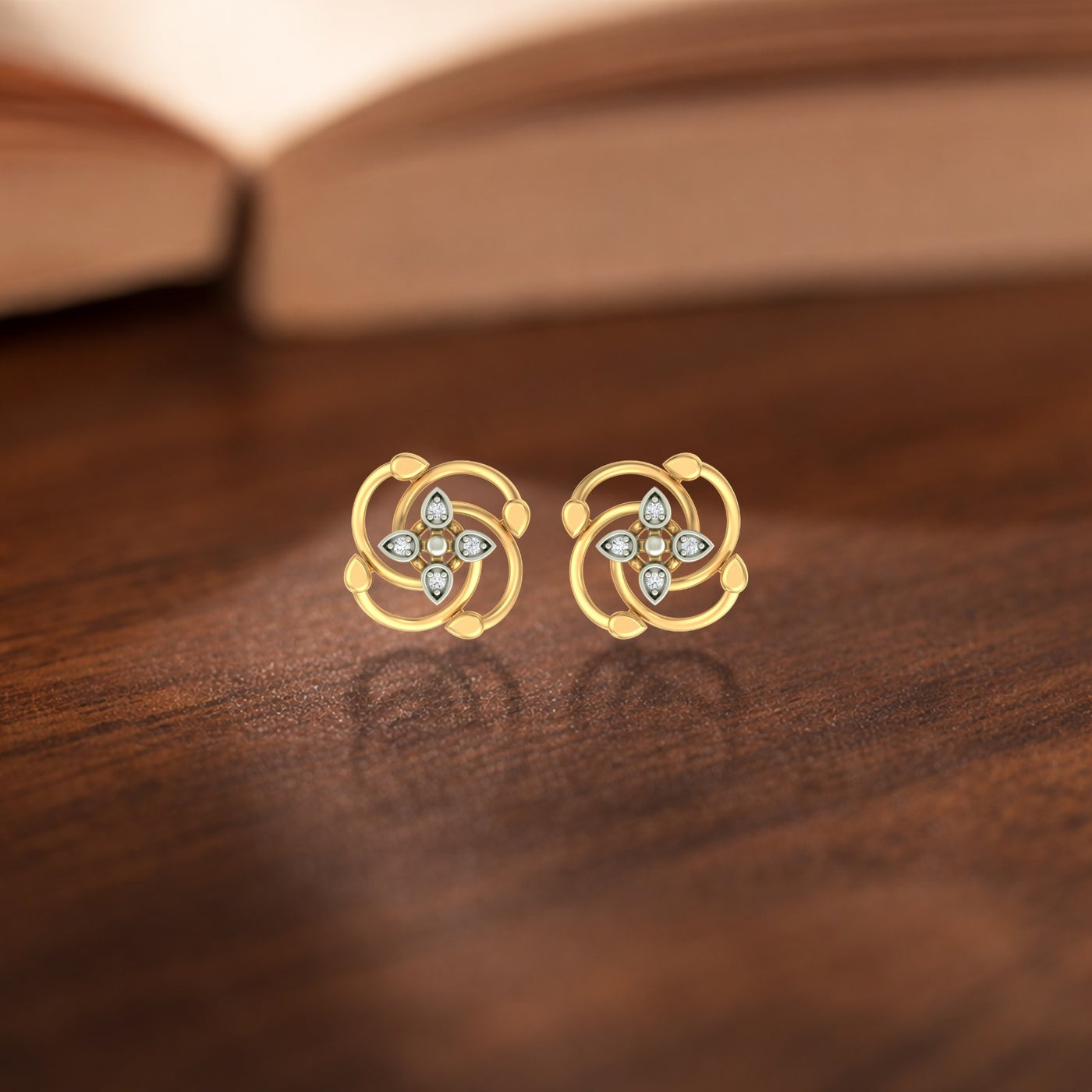 Gold and diamond earrings with floral design on a wooden surface.