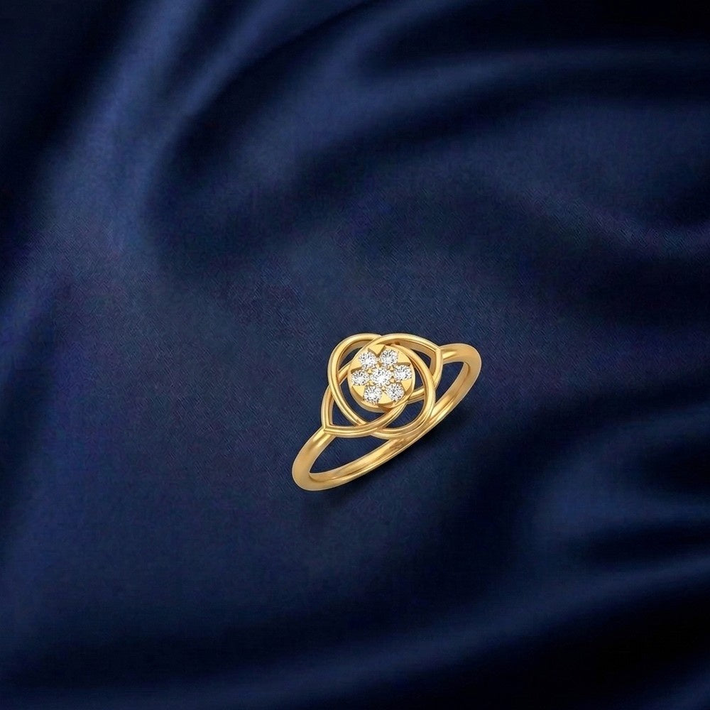 A yellow gold ring with a floral-inspired, diamond-studded center piece, set against a dark blue fabric background