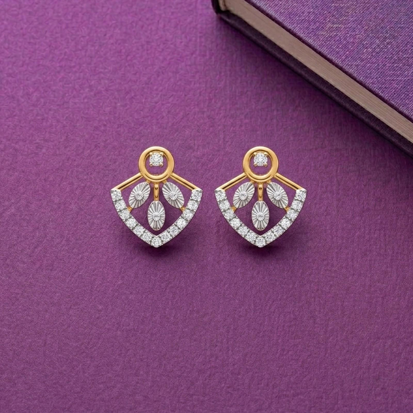 Gold and diamond earrings with diamond accents on a purple background.