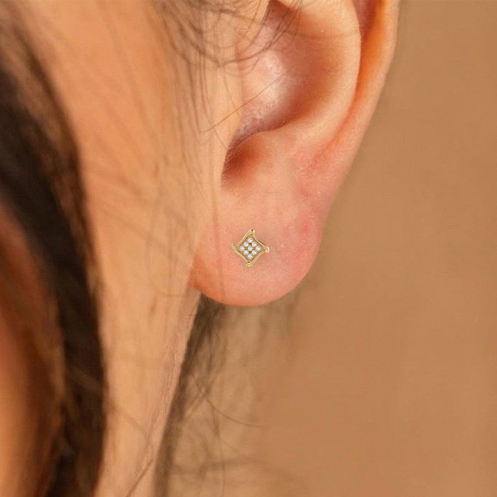 Close-up shot of a gold and diamond stud earring.