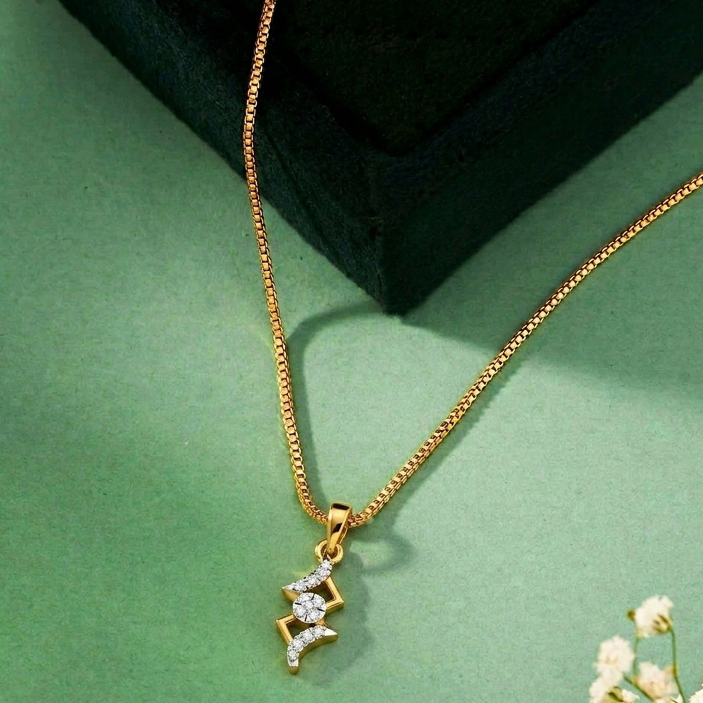 Gold and diamond necklace on a green surface