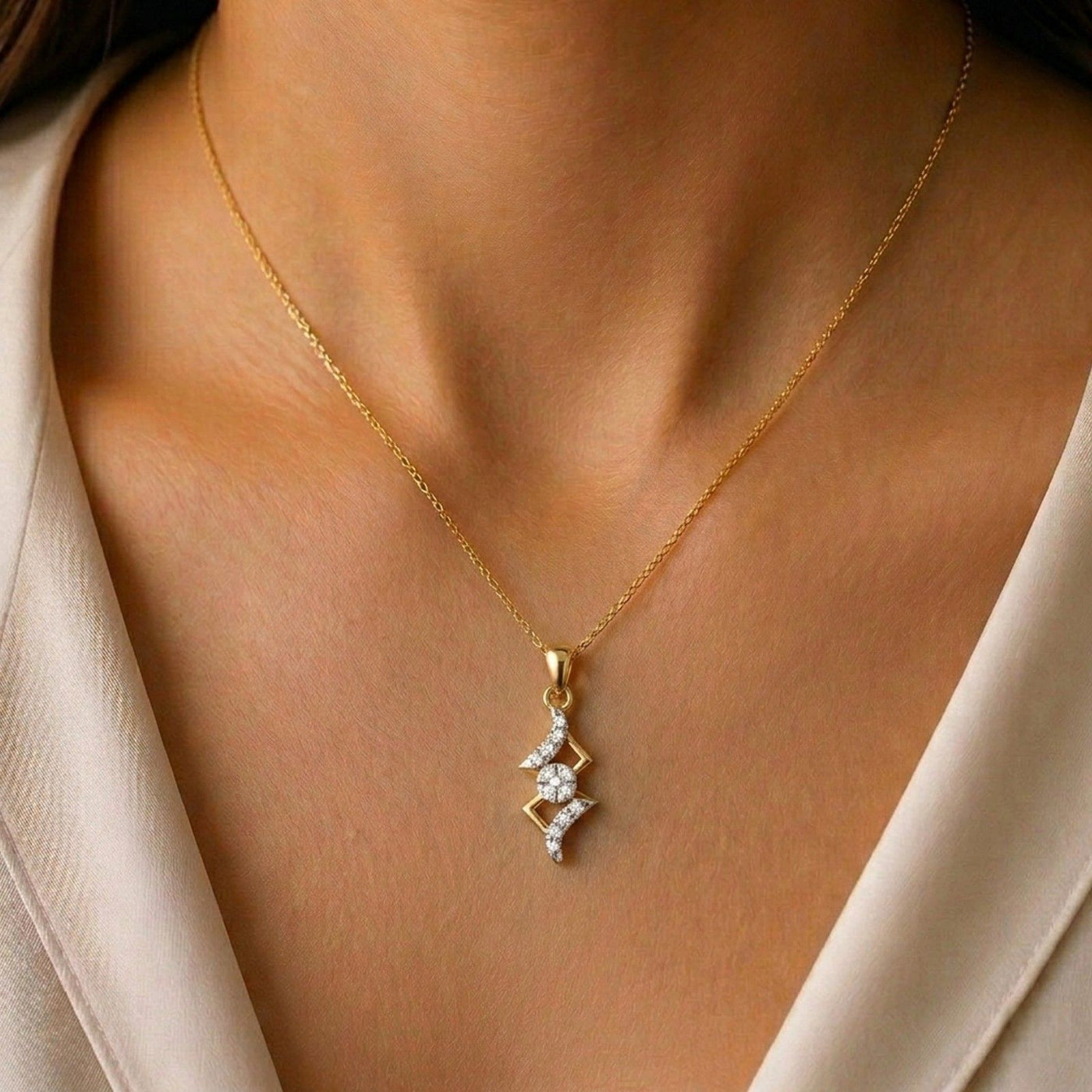Gold necklace with a diamond pendant on a person wearing a beige outfit.