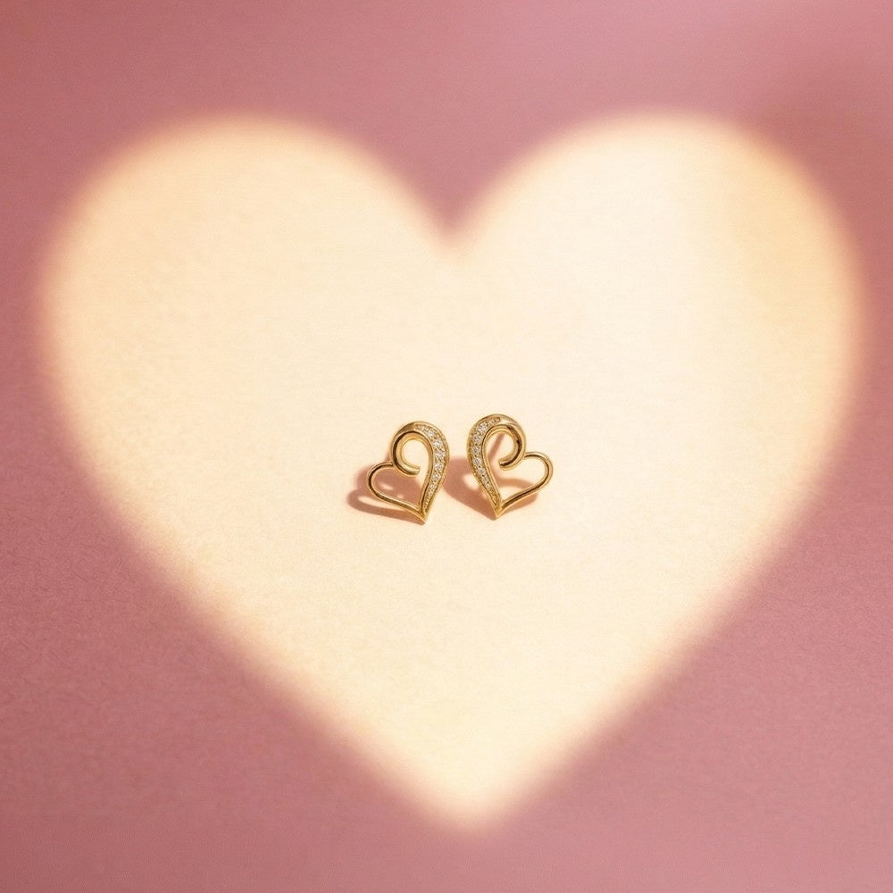 Gold and diamond heart-shaped stud earring on a pink background with heart-shaped light.