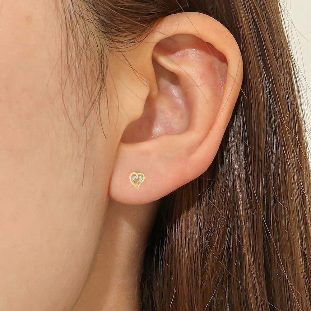 Close-up shot of a gold and diamond heart-shaped stud earring.
