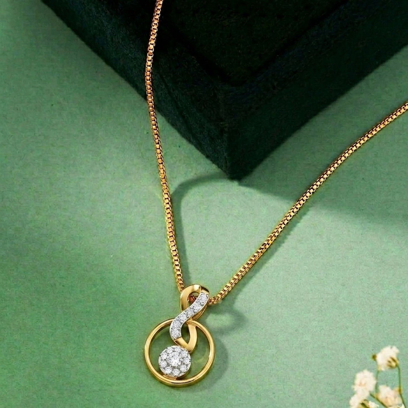 Gold  and diamond pendant on a green surface