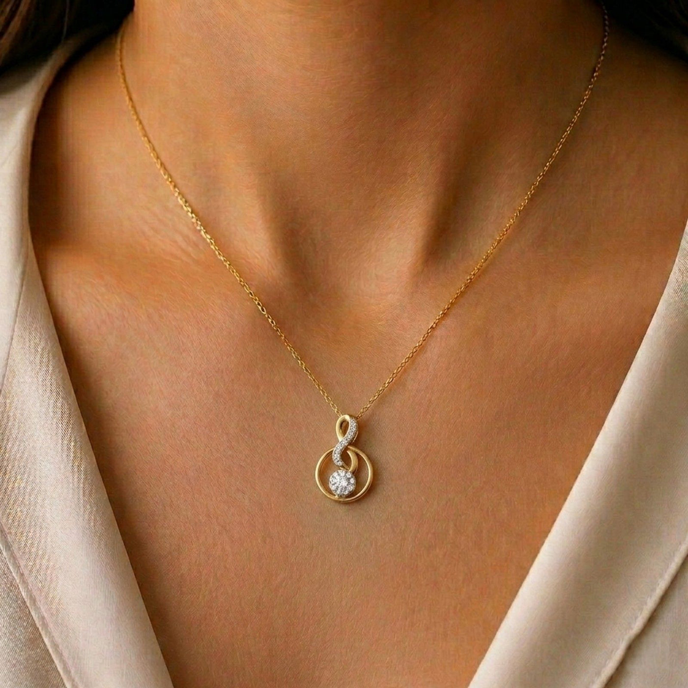 Gold and diamond pendant on a person wearing a beige top.