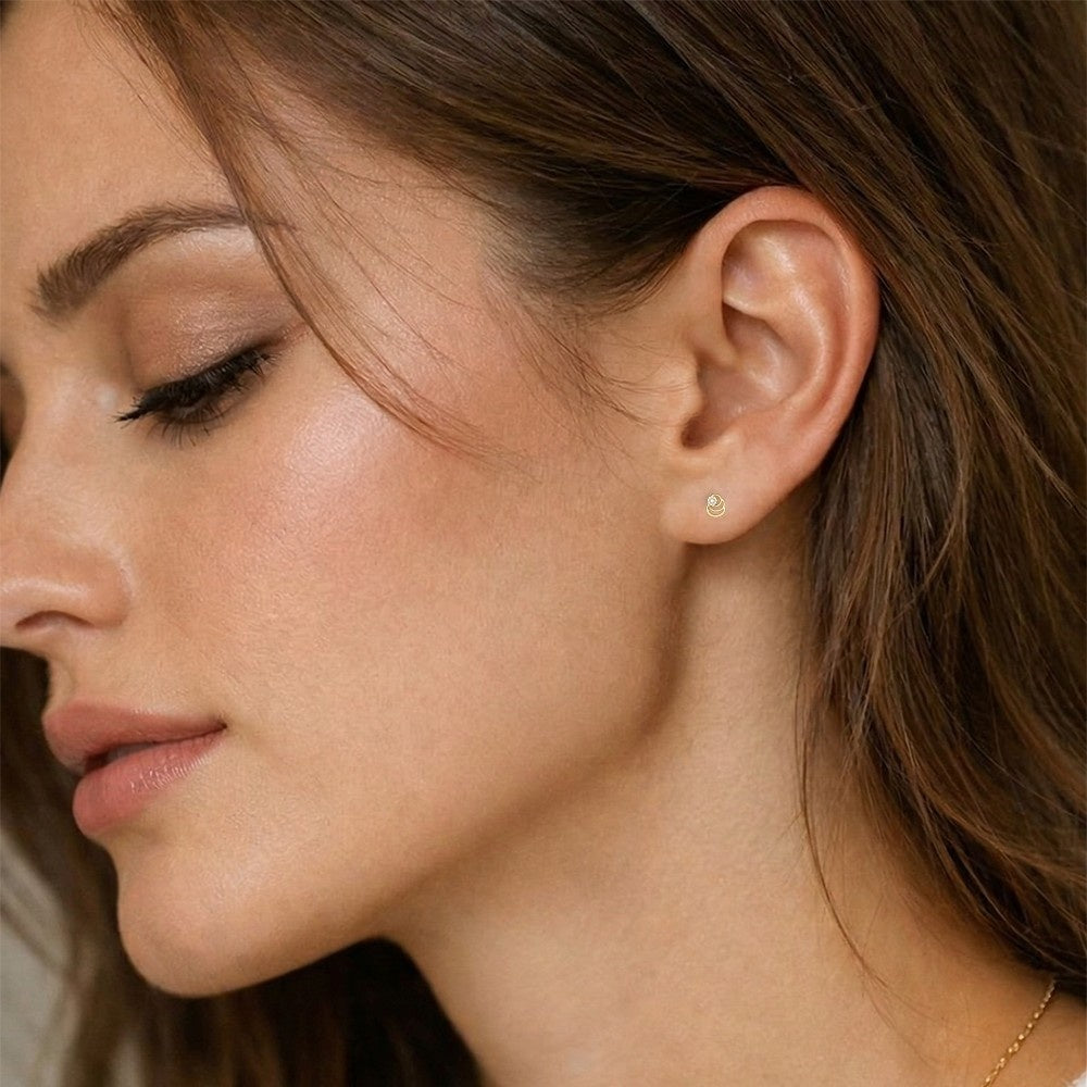 Close-up of a woman wearing a gold and  diamond stud earring.