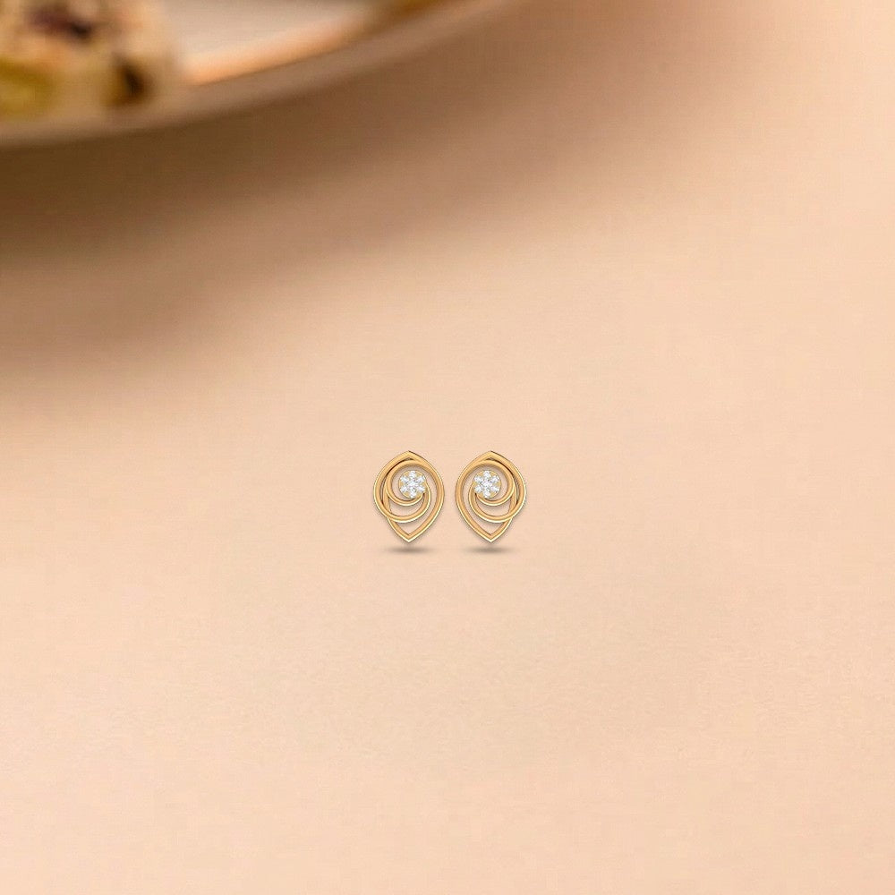 Gold and diamond stud earrings with circular design  on a beige background.