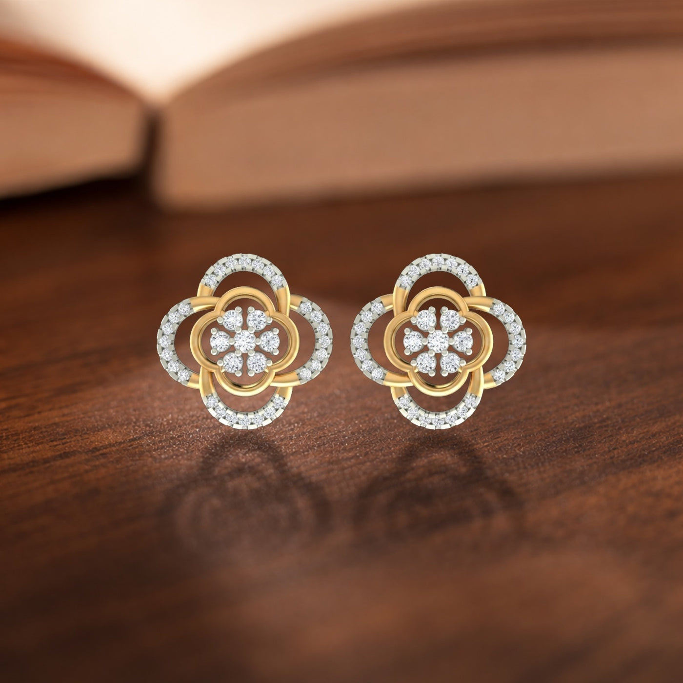 A pair of two-tone gold and diamond floral stud earrings resting on a dark wooden surface