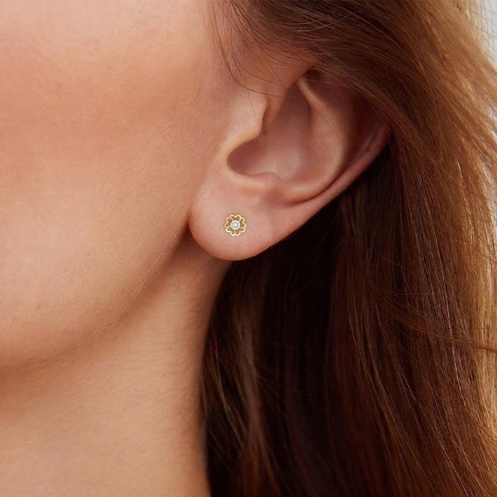 Close-up of a person wearing a gold and diamond floral stud earring.