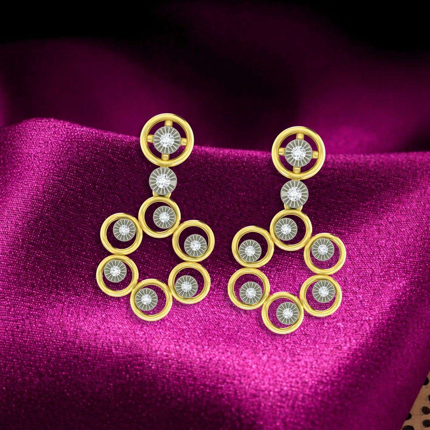 A pair of two-tone gold and diamond cluster drop earrings resting on vibrant magenta fabric