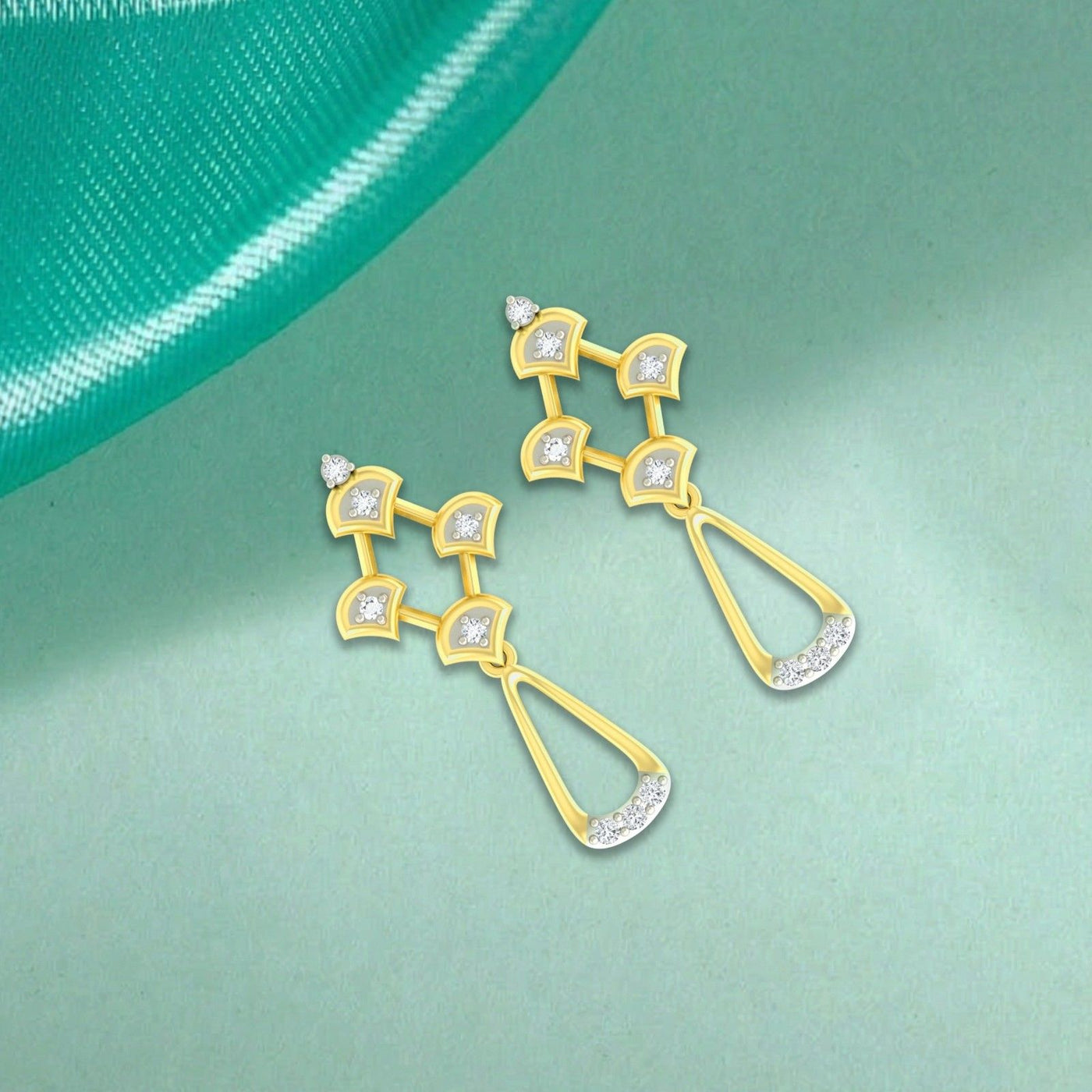 A pair of gold and diamond drop earrings with clear gemstones, displayed on a light green surface.