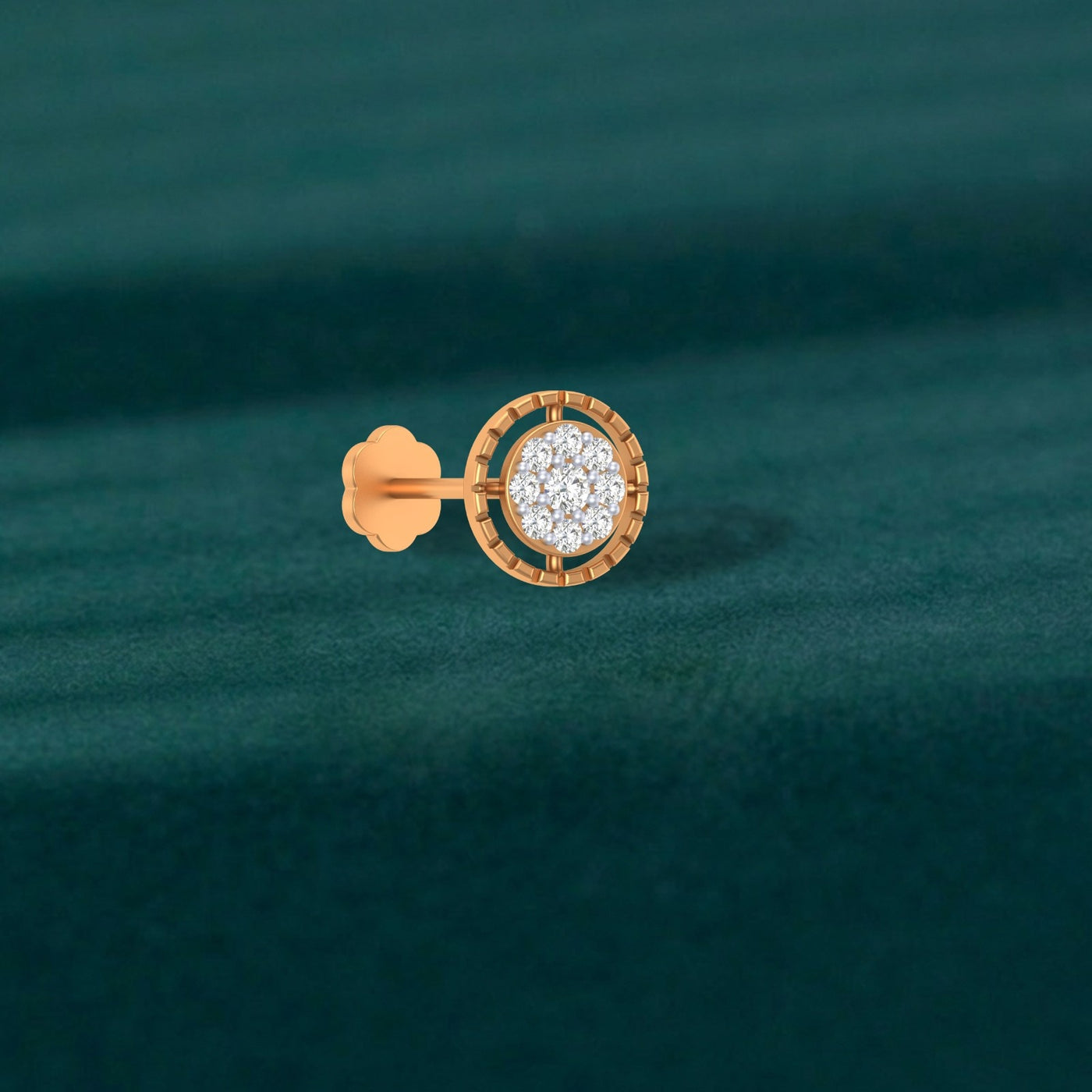 Gold and diamond stud nosepin-like stones on a teal fabric background